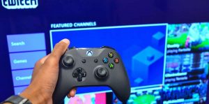 man holding a xbox one controller in front of twitch streaming screen