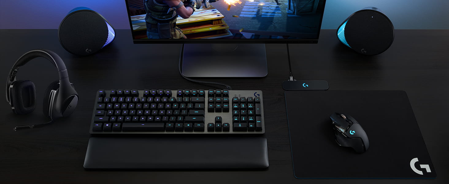 Logitech G502 Hero on the table next to a keyboard headset monitor and speakers